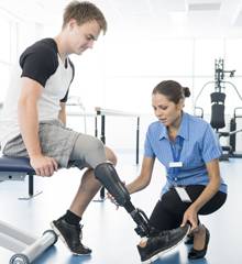 Physiotherapist attending to young man's prosthetic leg