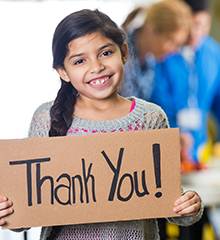 smiling girl holding homemade thank you Sign