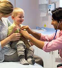 doctor with stethoscope listening to young boy's heart 