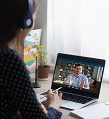 woman wearing headphones and talking virtually via laptop computer